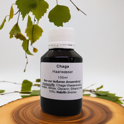 Chaga Haarwasser 100 ml in dunkler Glasflasche mit weißem Schraubverschluss, enthält Chaga-Wasserauszug, Ampfer, Minze, Glycerin und Ethanol für die äußere Anwendung.